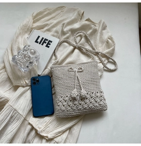 Detaillierte Nahaufnahme der cremefarbenen Stricktasche mit hohlen Blumenmustern und Deko