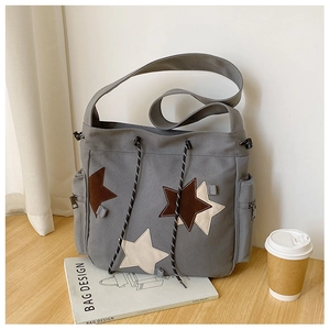 Detailed view of gray canvas crossbody bag with star patches and drawstring closure
