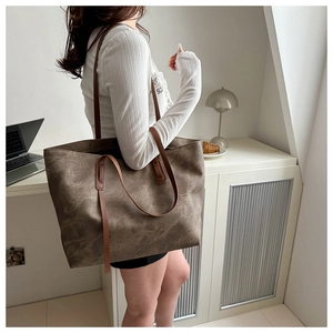 Dettaglio della texture in pelle marrone e dei lunghi manici di questa borsa tote
