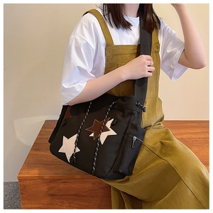 Detail of black canvas crossbody bag featuring colorful star patches and drawstring closure