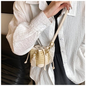 Close-up of woven straw bucket bag with white leather straps and gold hardware detail