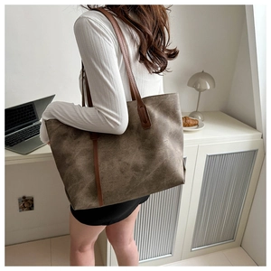 Dettaglio della borsa tote a contrasto marrone e taupe portata a spalla da modella