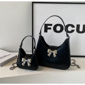 Detail view of two black bow accent handbags with silver chain in modern setting