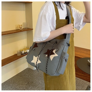 Detail view of a gray canvas messenger bag with large stars and adjustable drawstrings