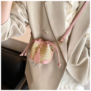Detail of pink faux leather and straw bucket bag with drawstring closure on model