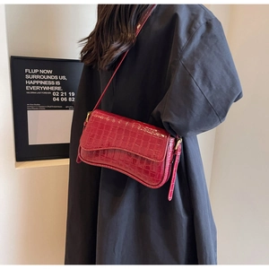 Detail of dark red crocodile pattern patent leather shoulder bag with gold metal buckle