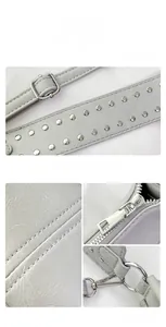 Detail view of adjustable rivet shoulder strap and silver metal hardware on a grey bag