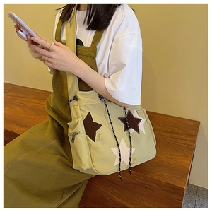 Detail of olive green canvas crossbody bag featuring star patches and drawstring closure