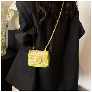 Dettaglio mini borsa in paglia intrecciata con finiture in PU verde e fibbia a fiore