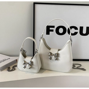 Detail view of white crescent bags with silver bow buckle and elegant metal chain