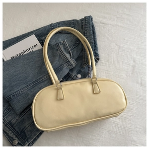 Minimalist beige PU leather oval baguette bag with silver hardware on blue denim jacket