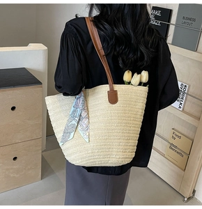 Detail of oatmeal straw woven tote bag with brown leather straps and floral silk scarf