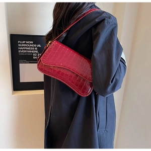 Detailed view of wine red crocodile embossed underarm bag with glossy patent leather finish