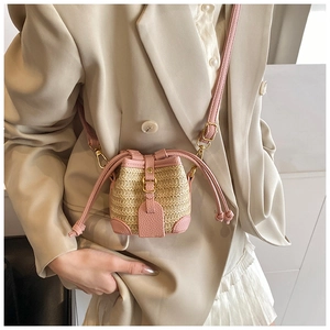 Detail shot of mini straw bucket bag with pink lychee texture leather on beige suit outfit
