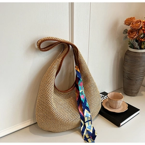 Fashionable straw shoulder bag with brown leather handle and blue floral scarf decoration
