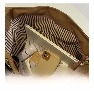 Detailed interior of large canvas crossbody bag with striped lining and storage pockets