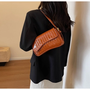 Caramel brown crocodile embossed faux leather shoulder bag worn on a female shoulder