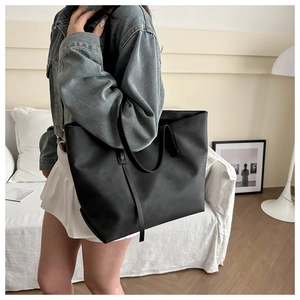 Borsa tote nera minimalista indossata da una modella in un salotto moderno