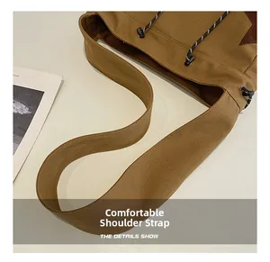 Detail view of the wide canvas strap and plastic buckle on this khaki messenger bag