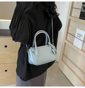 Detailed side view of light blue glossy PU leather crossbody bag with bow accessory