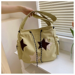 Detail of canvas messenger bag with star patches, side zipper pockets and drawstring closure