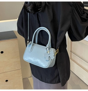 Macro detail of light blue oil wax leather texture and logo on the trendy crossbody bag