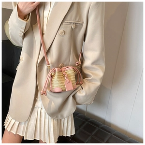 Detail view of mini straw bucket bag with pink leather trim and drawstring closure
