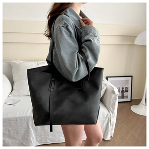 Vista laterale di una grande borsa tote in pelle nera indossata da una modella