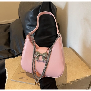 Macro shot of pink hobo bag with a silver metallic bow and elegant chain strap detail