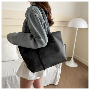 Grande borsa tote nera opaca minimalista indossata da un modello per riferimento taglia
