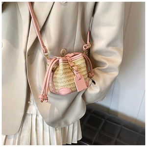 Detail of a mini straw bucket bag with pink leather drawstring and long shoulder strap