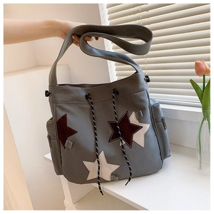 Detail of grey canvas crossbody bag with three star patches and convenient side zipper pocket