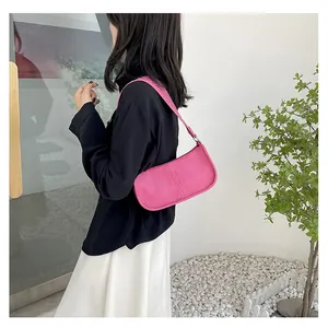Close-up of pink crossbody baguette bag featuring silver studs on the shoulder strap