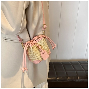 Detail of pink lychee leather and straw woven bucket bag with drawstring closure