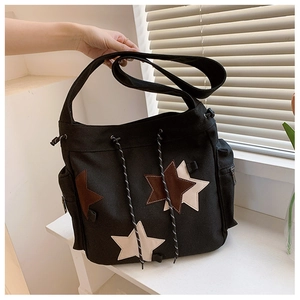Detail view of black canvas crossbody bag featuring star patches and drawstring closure