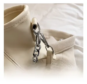 Detail von silbernem Metallhaken und Kettenverbindung an beiger PU-Lederhandtasche