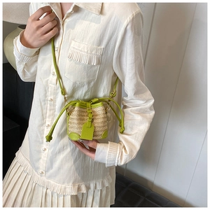 Detail shot of mini straw bucket bag with lime green leather trim and shoulder strap