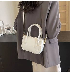 Detail of white PU leather crossbody bag with bow charm and brand logo on model