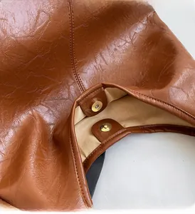 Close-up of brown crinkled faux leather texture and golden magnetic snap closure