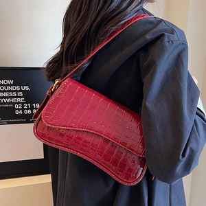 Elegant red crocodile pattern baguette bag worn as a shoulder bag with a sleek finish