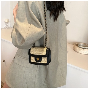 Dettaglio mini borsa in paglia intrecciata beige con chiusura a fiore dorato