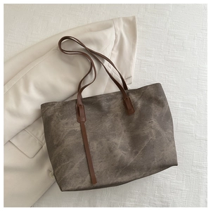 Borsa tote tortora minimalista con manici in pelle marrone su sfondo beige