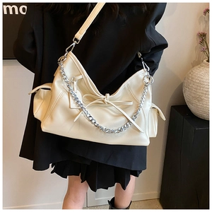 Detail der cremefarbenen PU-Ledertasche mit Seitentaschen und elegantem Schleifendetail