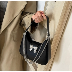 Detail of black crescent hobo bag with silver metal bow and chunky chain strap