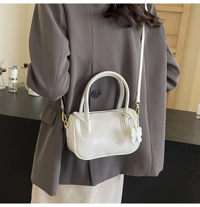 Detail of white PU leather Boston bag with a cute bow charm and golden metal hooks