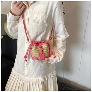 Detail of pink leather trim and straw texture on a mini bucket bag with drawstring