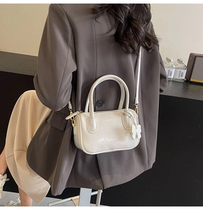White minimalist PU leather crossbody bag worn with a chic business suit as a stylish accessory