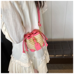 Detail of a bright pink straw bucket bag featuring woven texture and gold metal hardware