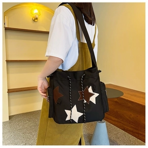 Large black canvas messenger bag featuring star patches and drawstring for students