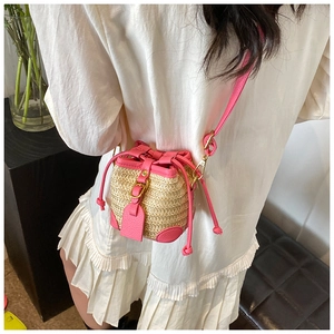 Detail of straw bucket bag featuring fuchsia leather trim and a gold buckle accent